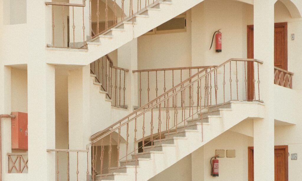 Interior staircases and corridors in a multi-storey staff accommodation building with visible fire extinguishers.