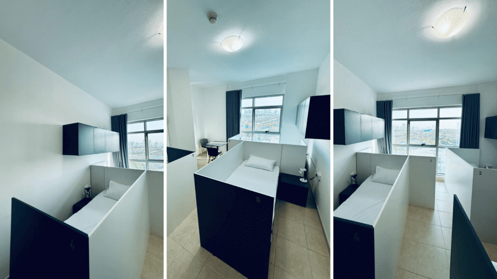 Clean partitioned staff accommodation room in Dubai with individual beds, storage, natural light, and organized workforce housing setup.