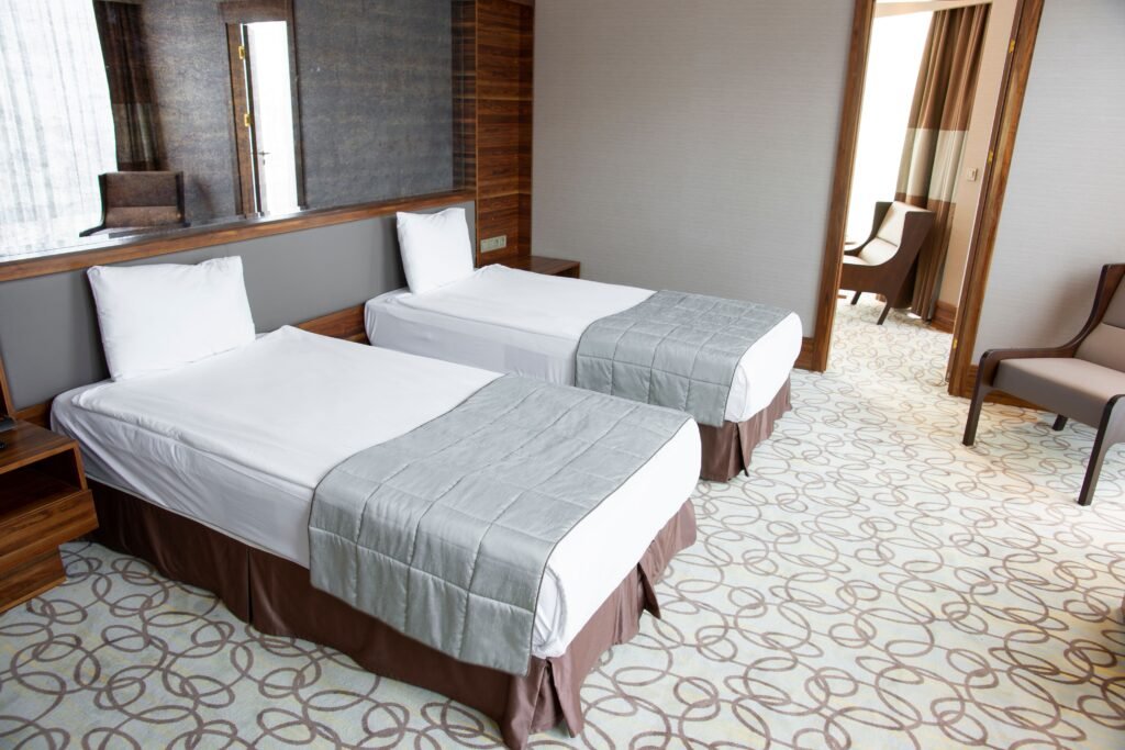 Clean twin room with two single beds, seating and large windows