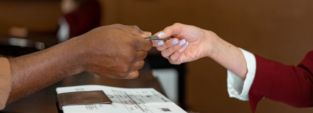 Two people exchanging a card across a reception desk during check-in