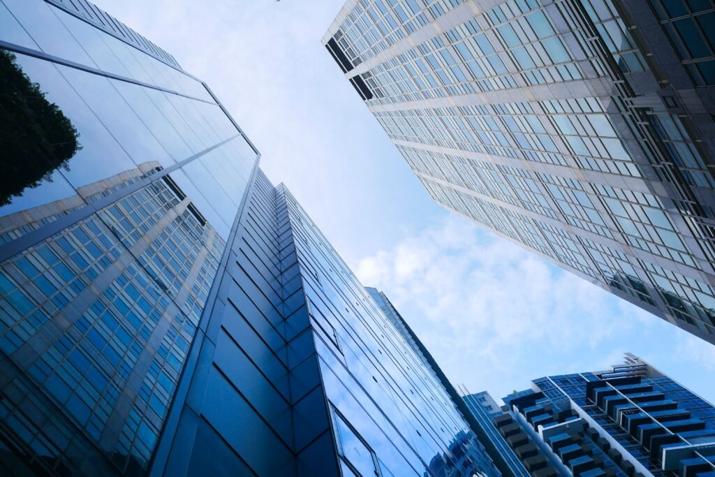 Low-angle view of modern glass office buildings against a blue sky.